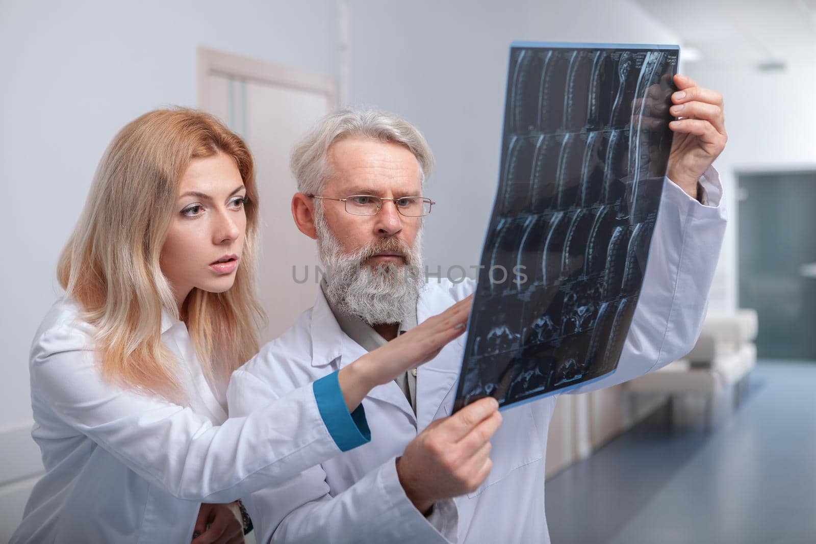 Senior male doctor and his young female intern examining MRI scan together