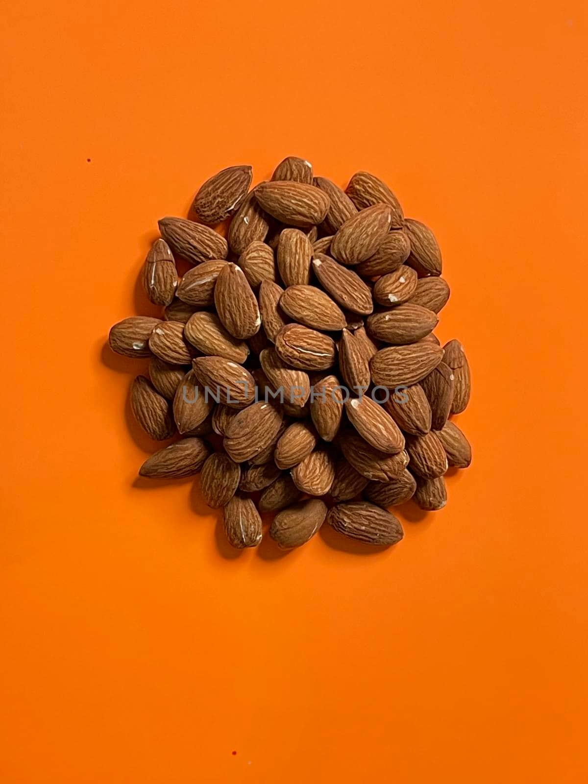 Peeled almond nuts on orange background