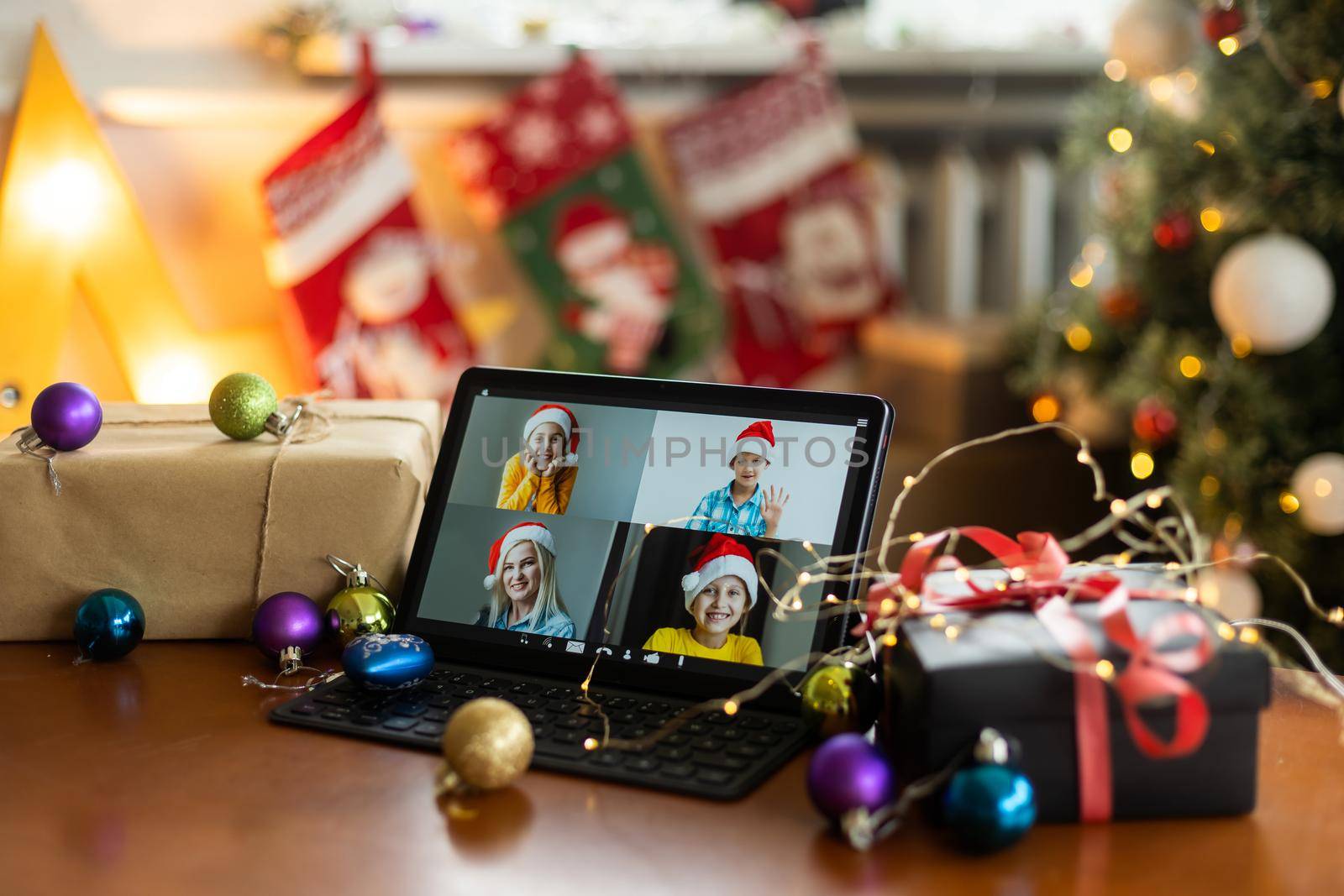 Christmas video call with happy family. Concept of families in quarantine during Christmas because of the coronavirus. Xmas still life with a tablet in a cozy room by Andelov13