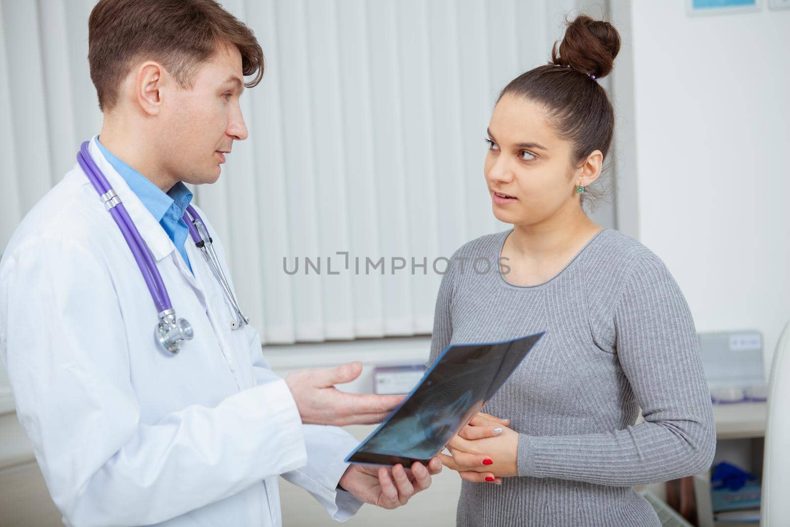 Female patient listening to the doctor attentively while he is explaining x-ray survey results