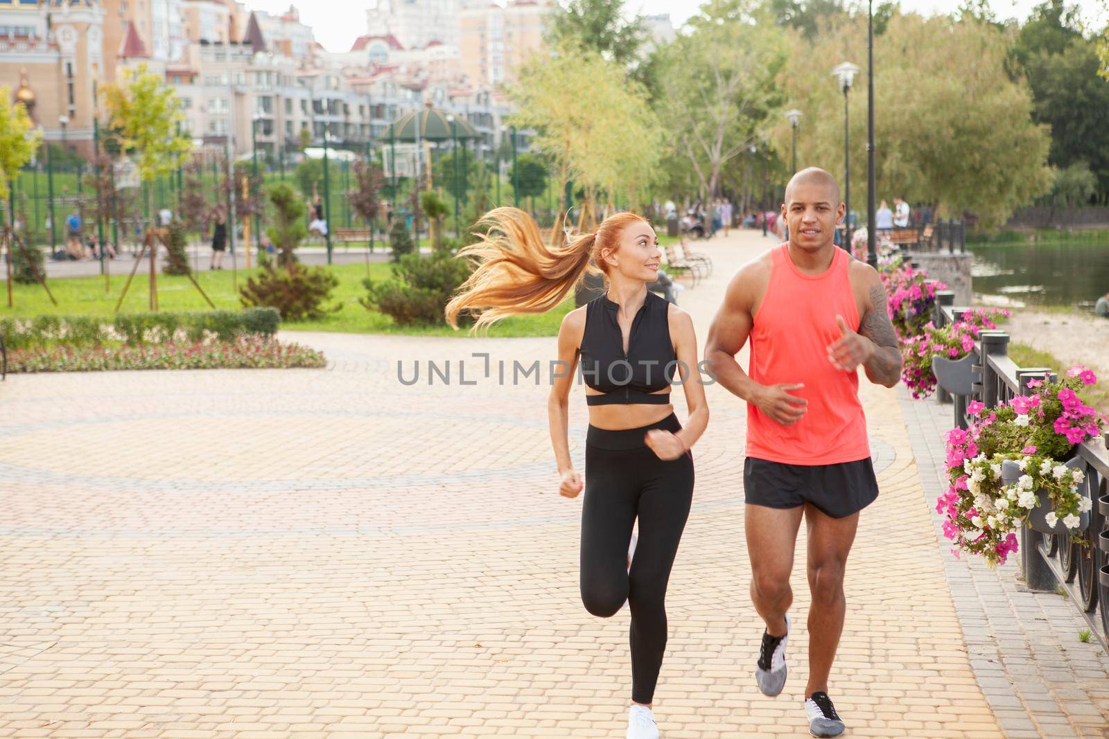 Full length shot of a beautiful healthy fit couple enjoying running outdoors in the morning, copy space. Handsome African muscular man and his beautiful girlfriend jogging together. Health, love, active lifestyle concept