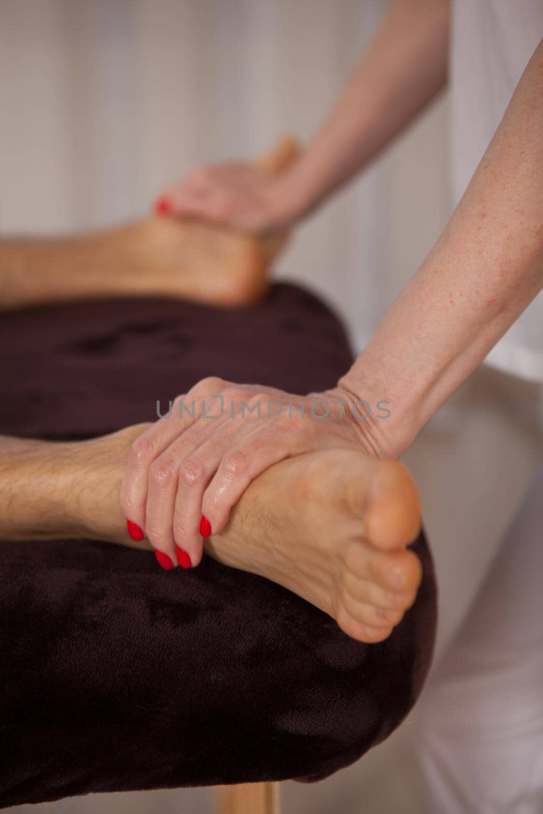 Vertical cropped close up of unrecognizable man getting foot massage at spa center