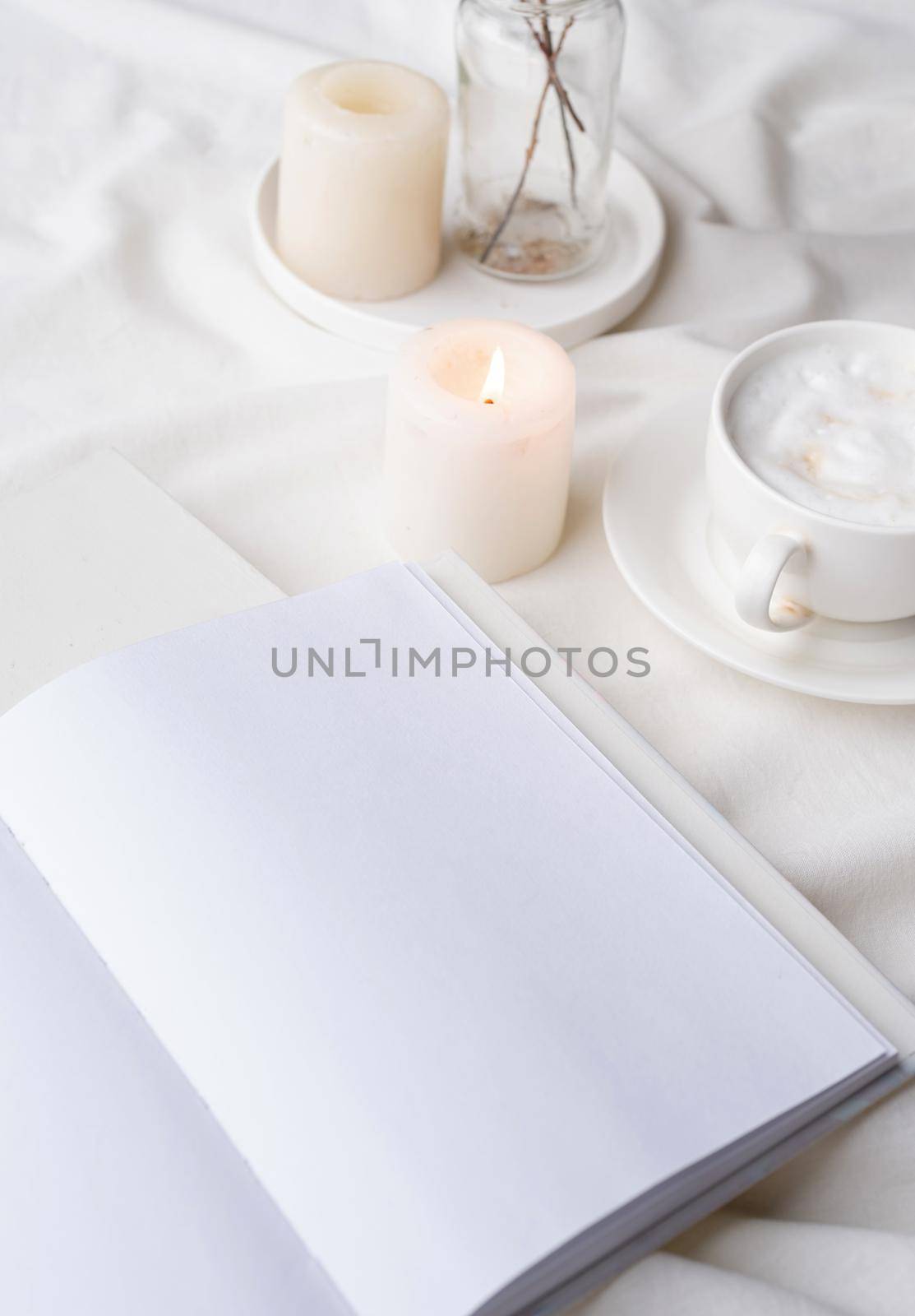 white blank book with cup of coffee and burning candle , cozy composition with opened book mockup by Desperada