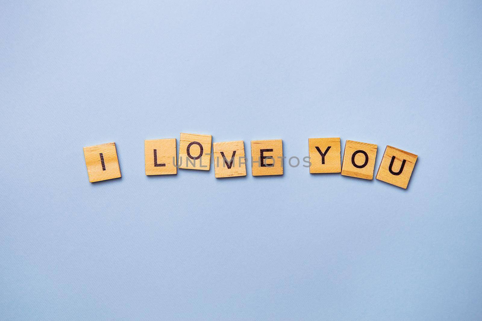 Inscription I love you in wooden square letters on a light blue background. Ready postcard, banner, place for an inscription. by sfinks