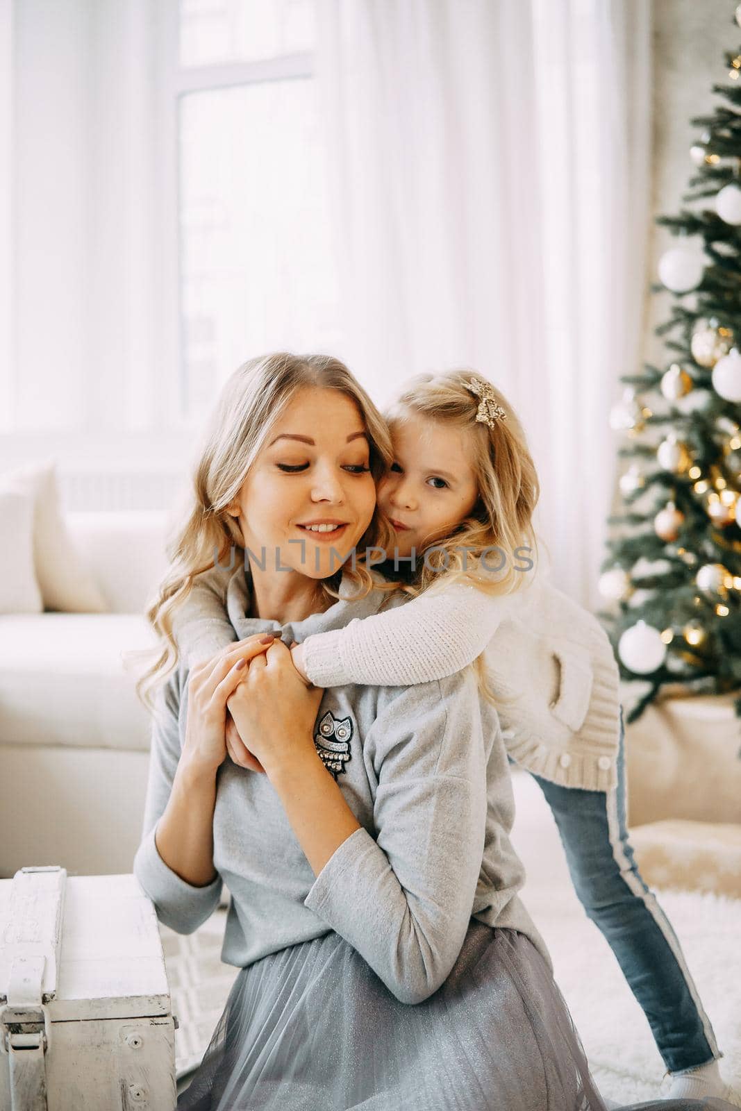 Happy family: mother and daughter. Family in a bright New Year's interior with a Christmas tree.