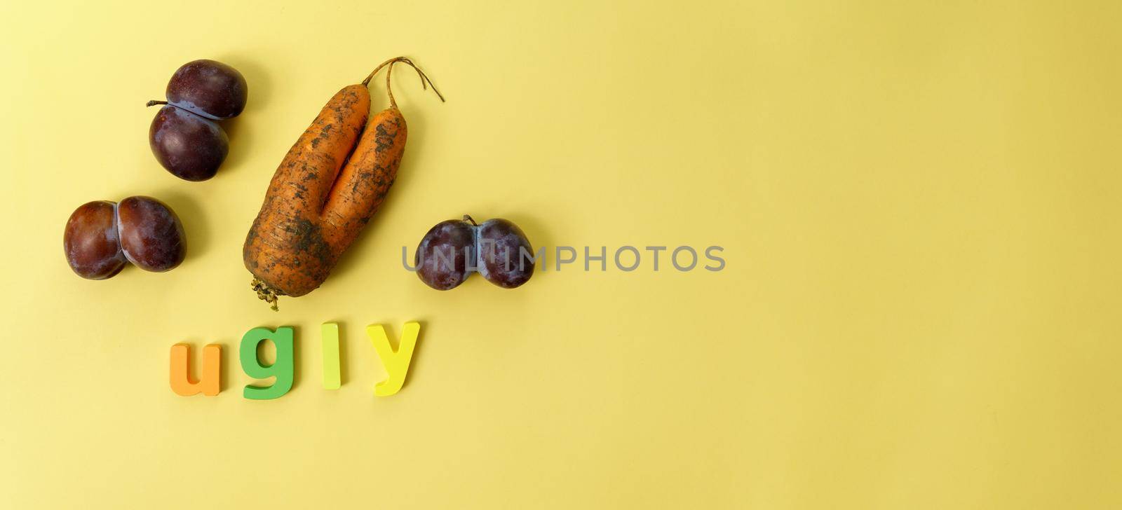 Ugly plums and carrot on yellow background. fruits are suitable for food. Concept Reduction of organic food waste. Copy space by darksoul72