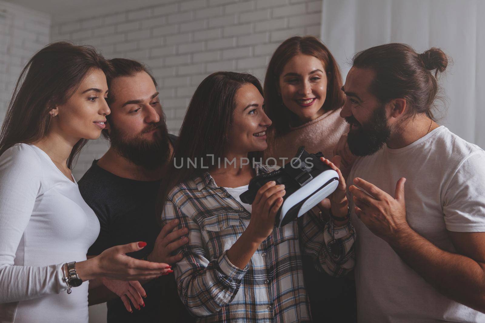 Beautiful woman smiling, talking to her friends after using virtual reality glasses. Group of creative business people discussing vr 3d goggles. Teamwork, entertainment, technology concept