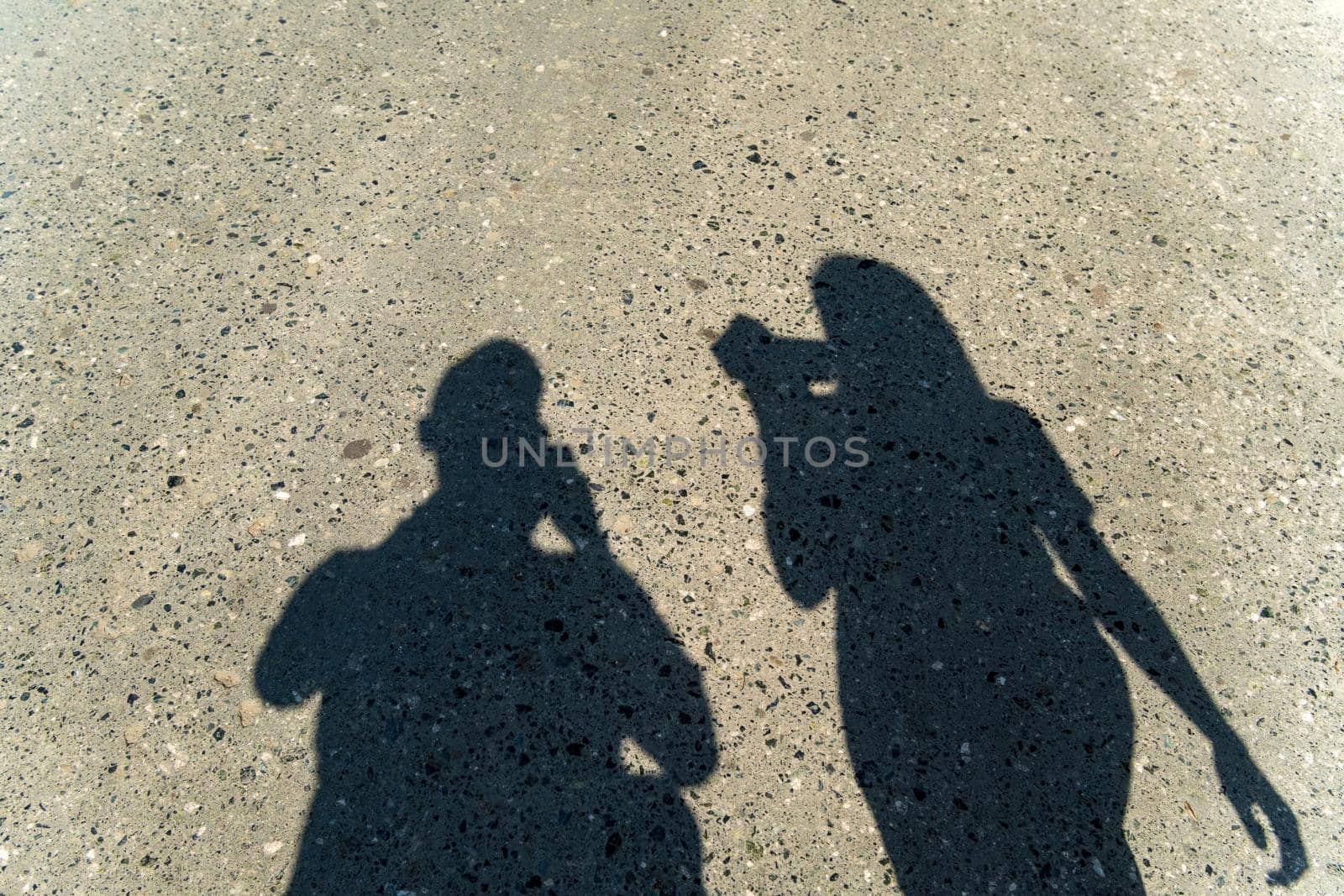 Abstract silhouettes man and woman asphalt street pavement on sunny day.