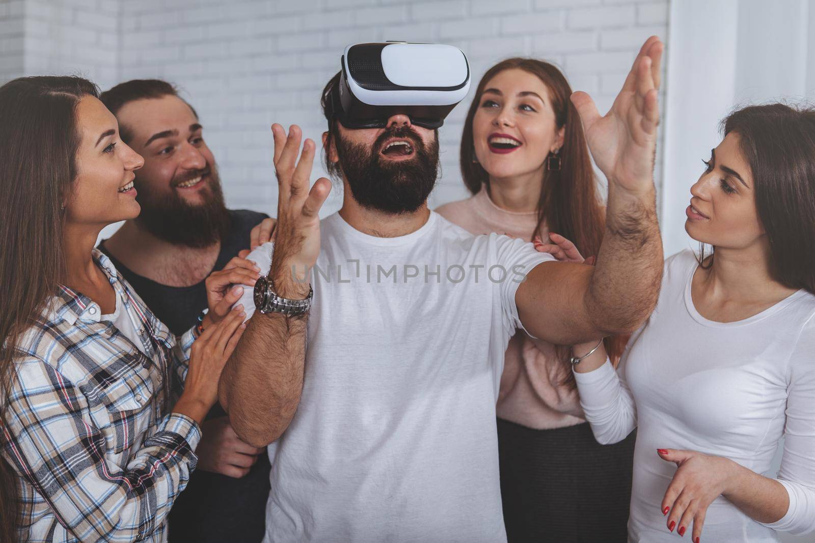 Creative business team using virtual reality glasses at the office. Bearded mature man wearing 3d vr headset, his colleagues surrounding him. Teamwork, startup, innovation concept