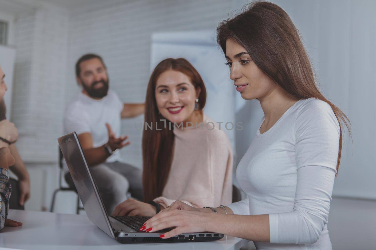 Attractive woman and her female colleague using laptop at the business meeting, copy space. Female entrepreneurs working on computer together at the office