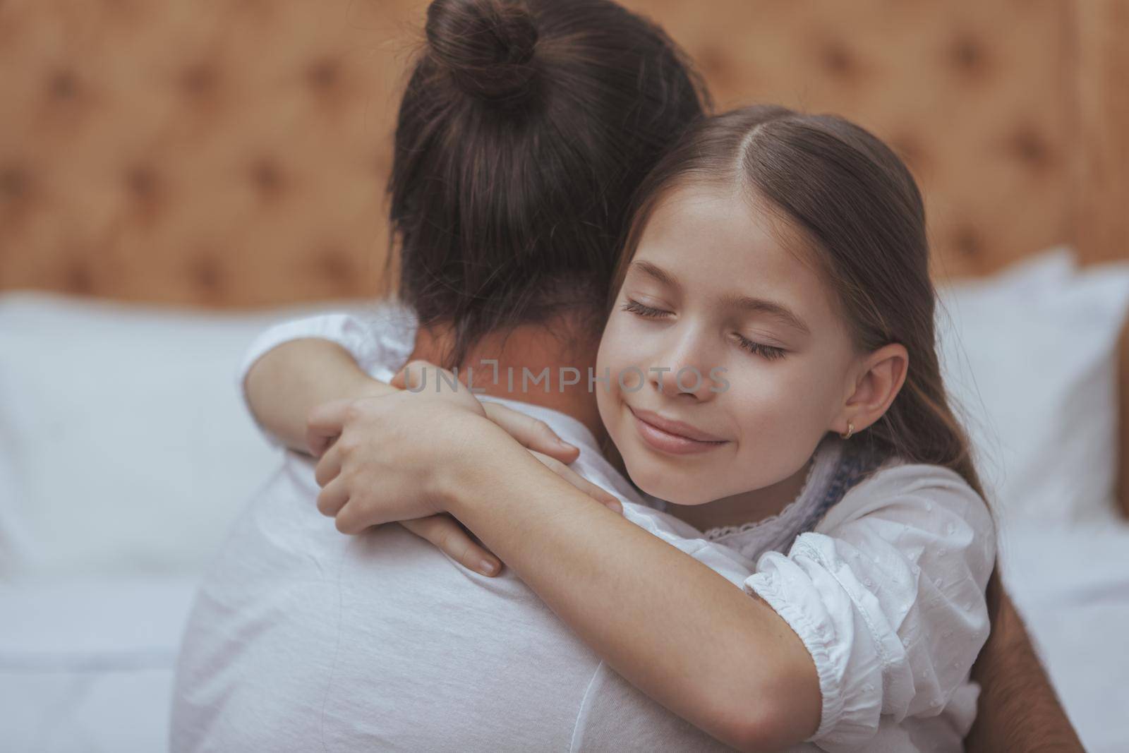 Close up of a beautiful little girl smiling with her eyes closed, hugging with her father. Rear view shot of a loving dad embracing his child. Loving father hugging his daughter