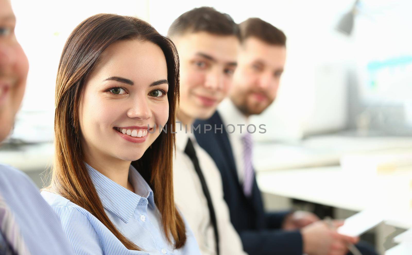 Portrait of pretty young business woman smiling at meeting with colleagues. Collaboration business training and consultation