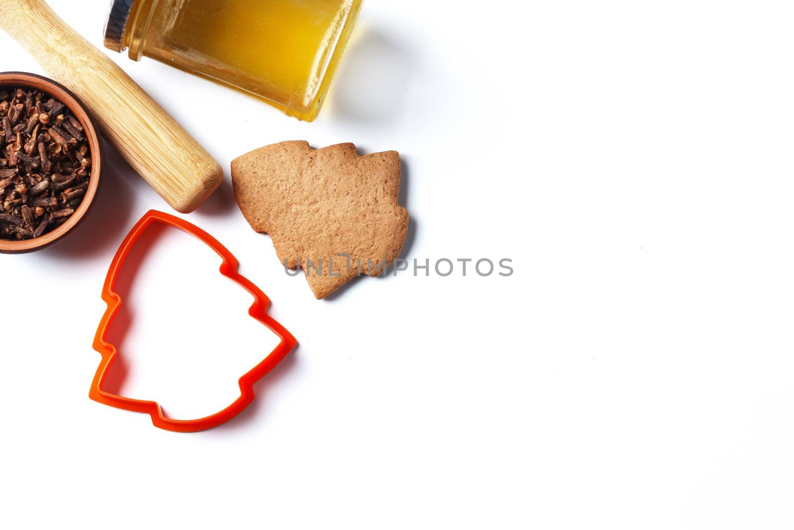 Ready-made Christmas cookies in the form of a Christmas tree with a cookie mold and ingredients: honey, cloves isolated on a white background. copy space.