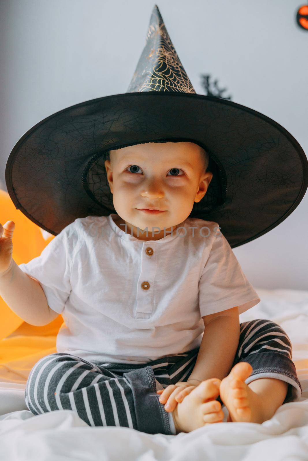 Children's Halloween - a boy in a witch hat and a carnival costume with airy orange and black balloons at home. Ready to celebrate Halloween by Annu1tochka