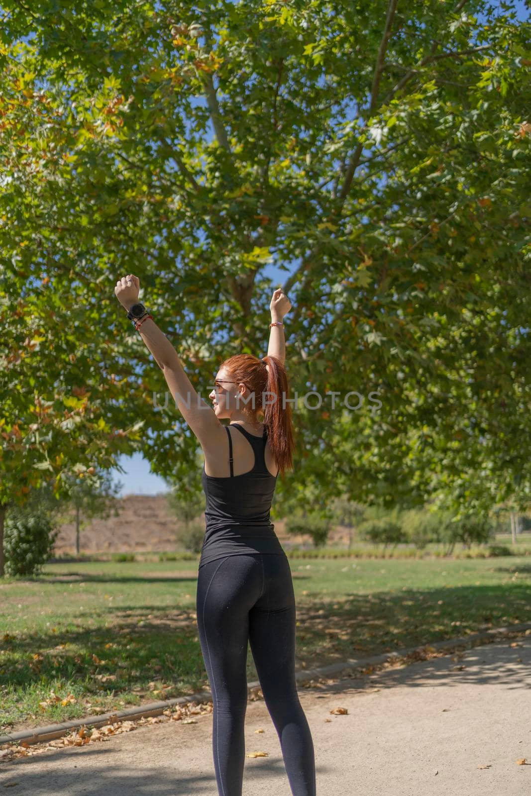 Happy sportswoman celebrating success in park by barcielaphoto