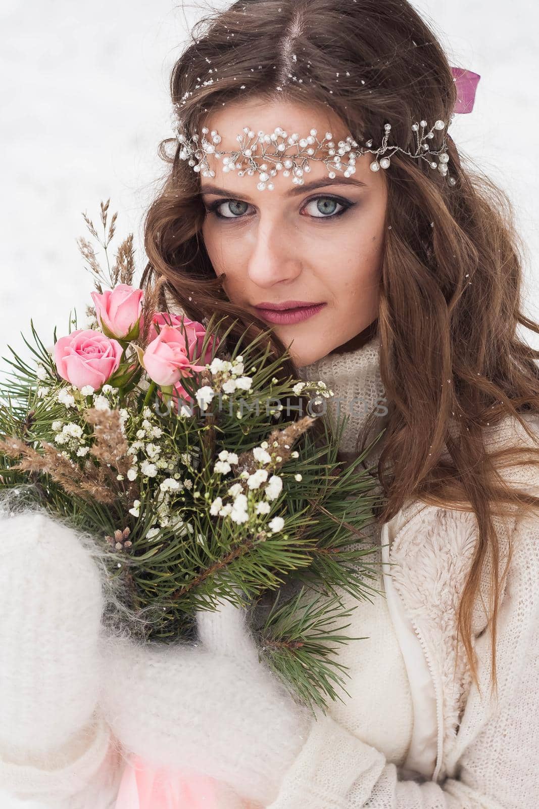 Beautiful bride in a white dress with a bouquet in a snow-covered winter forest. Portrait of the bride in nature.