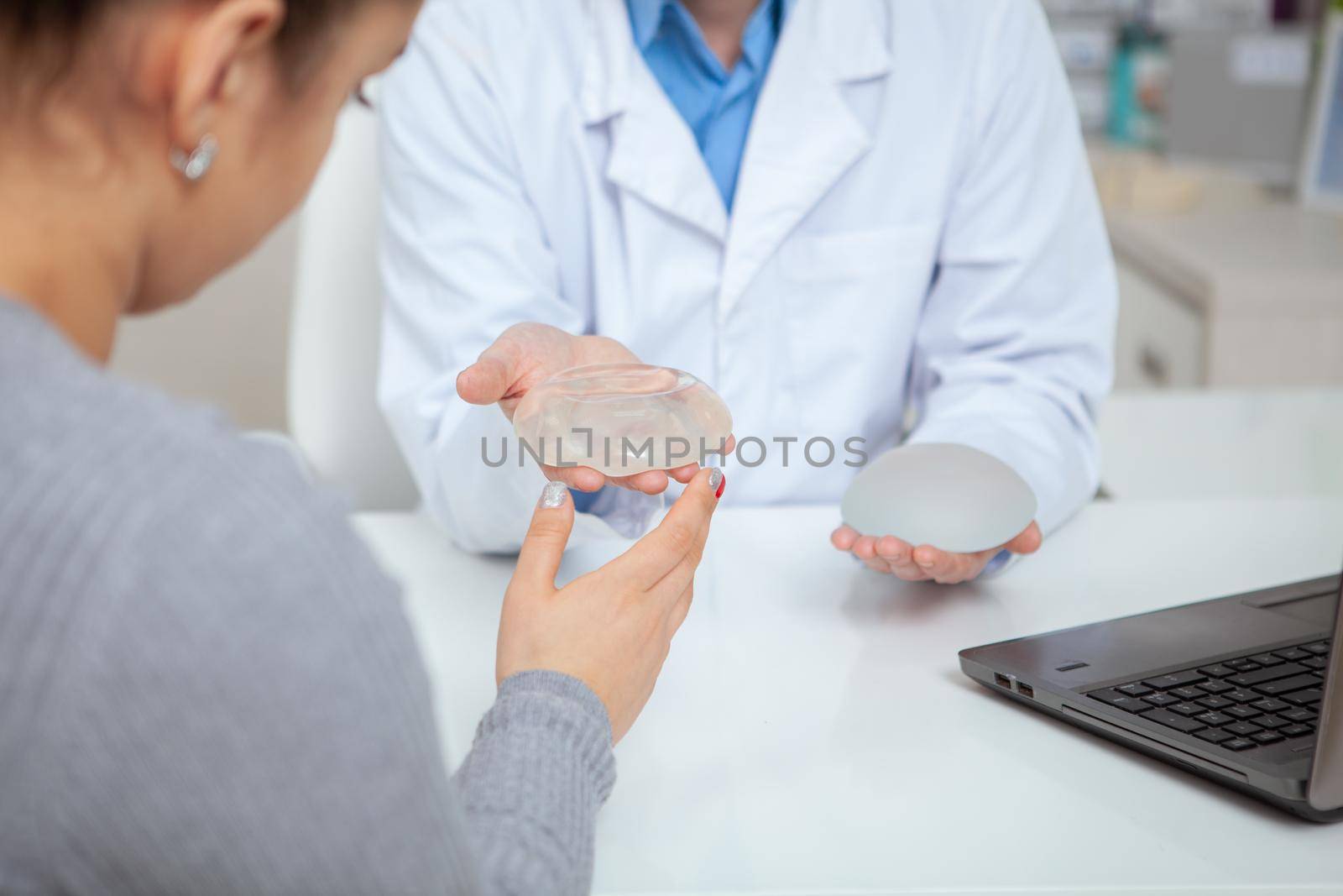 Cropped shot of a female patient examining silicone breast implants, during medical appointment with her plastic surgeon