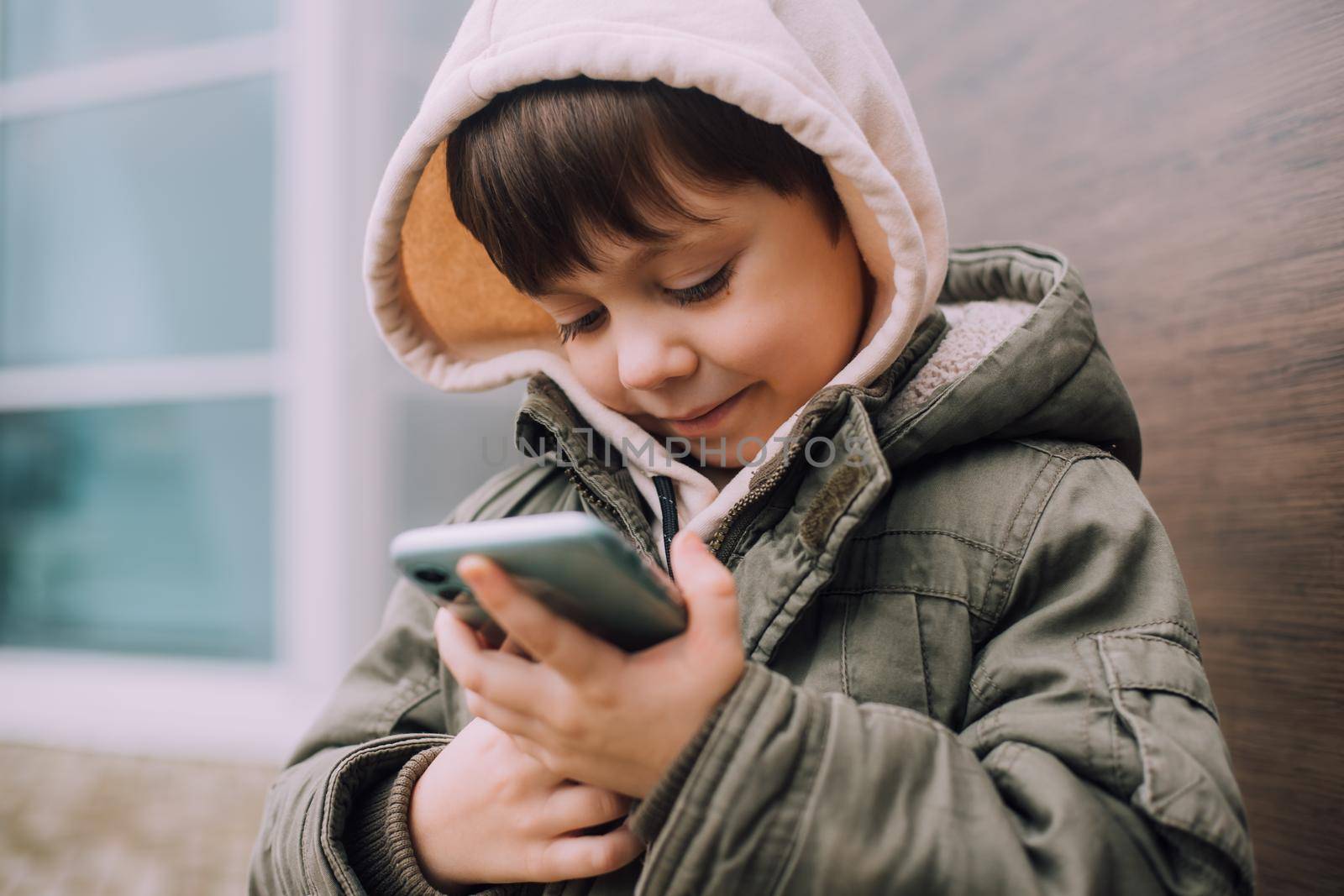 A boy looks at his phone in the city of lifestyle . Modern technologies. Modern children. A child and a phone. Urban lifestyle