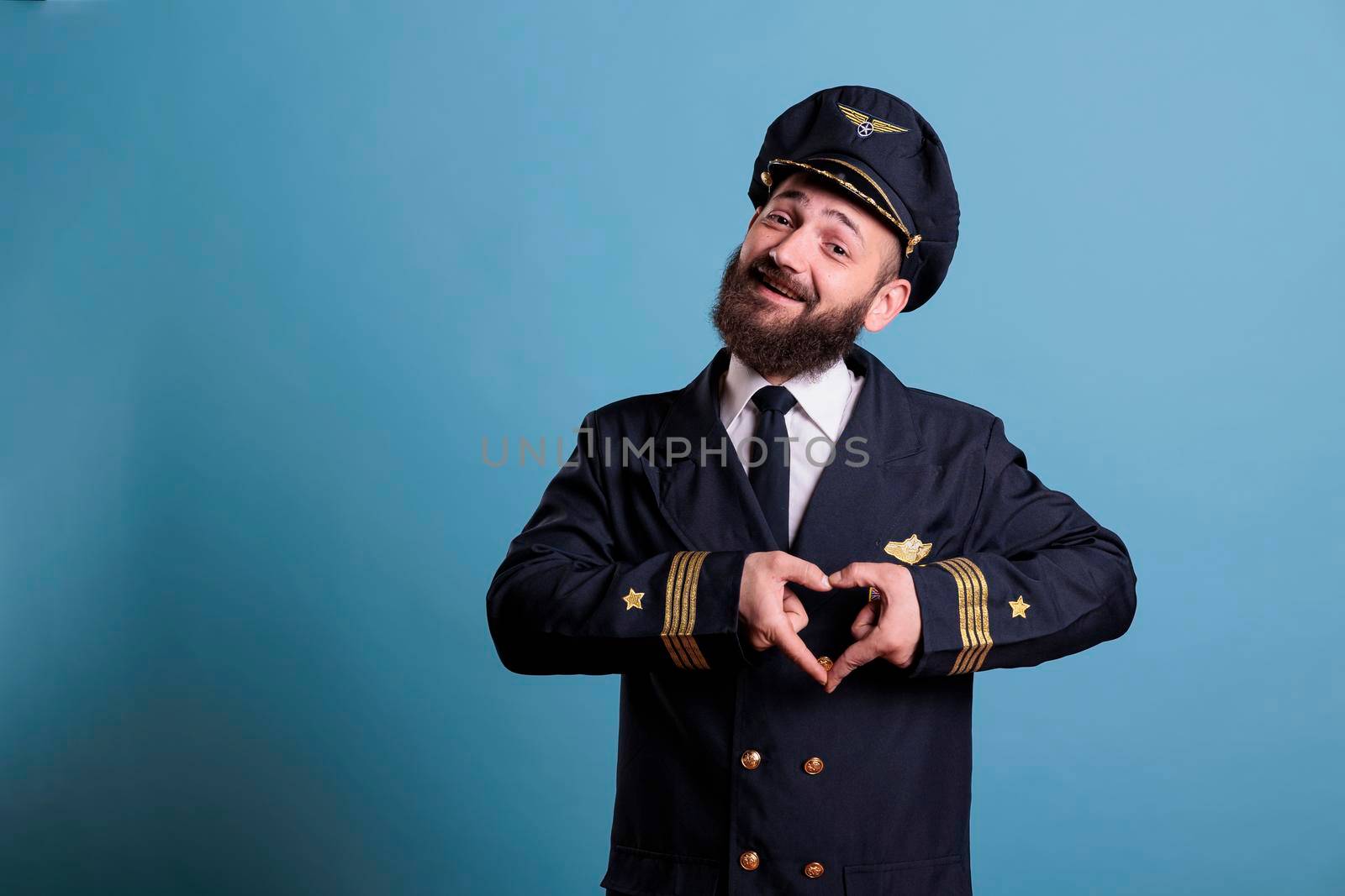 Smiling airplane pilot showing heart shaped love symbol by DCStudio