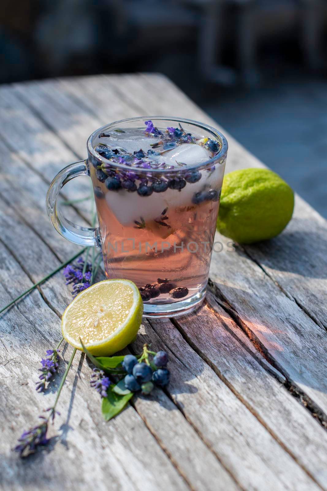 cold refreshing tea with blueberry, lime and lavender on a hot summer day on a wooden table. High quality photo
