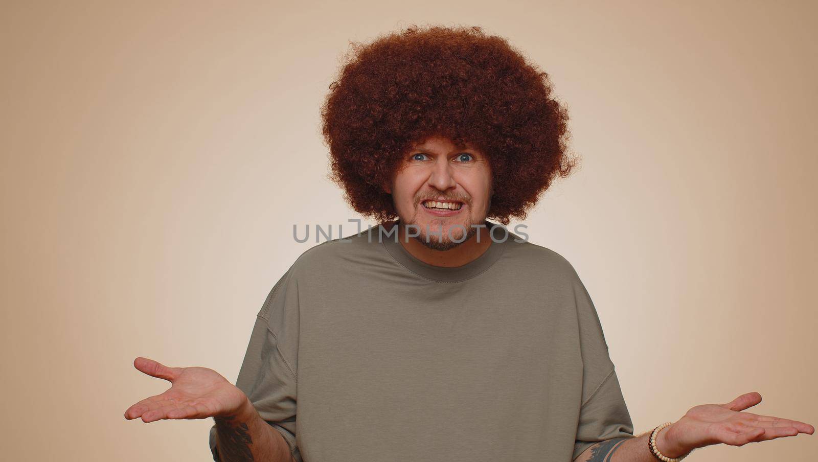 What Why. Sincere irritated adult man raising hands in indignant expression asking reason of failure demonstrating disbelief irritation by troubles. Young confused guy isolated on beige background