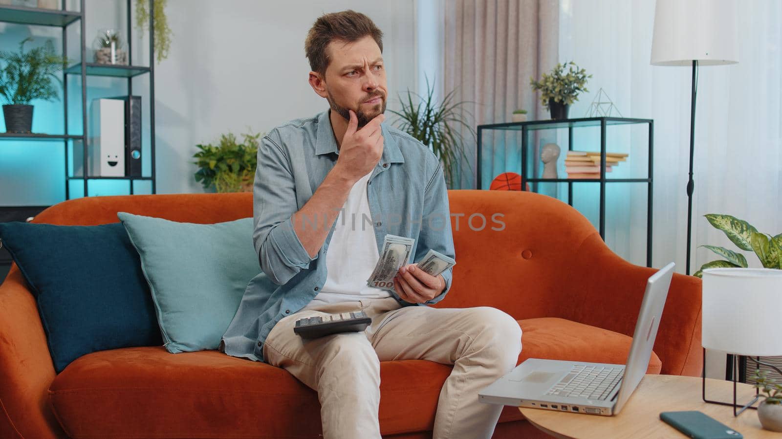 Planning budget. Rich happy man counting money cash use calculator and calculate domestic bills at home. Joyful young guy satisfied of income earnings, win, saves money for planned vacation, gifts