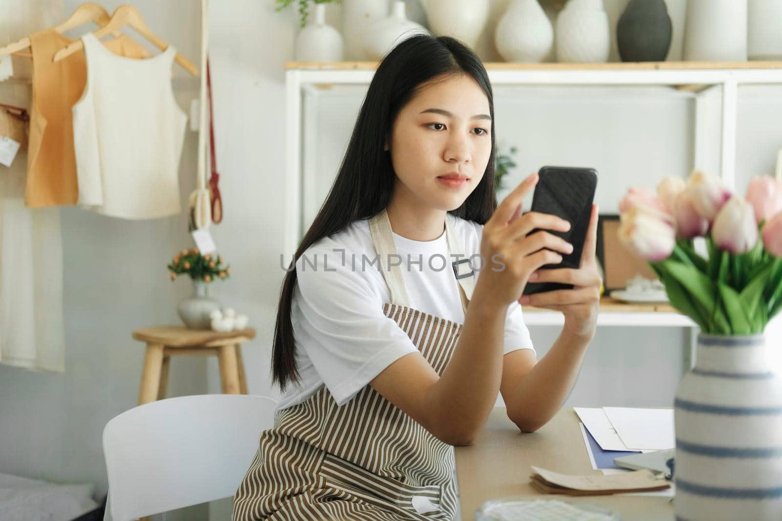 Young asian business owner holding phone and retail package parcel. by ijeab