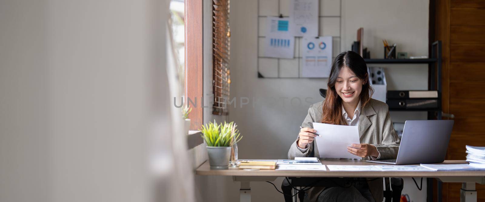 Attractive confident smiling asian woman paperwork chart report at home office.