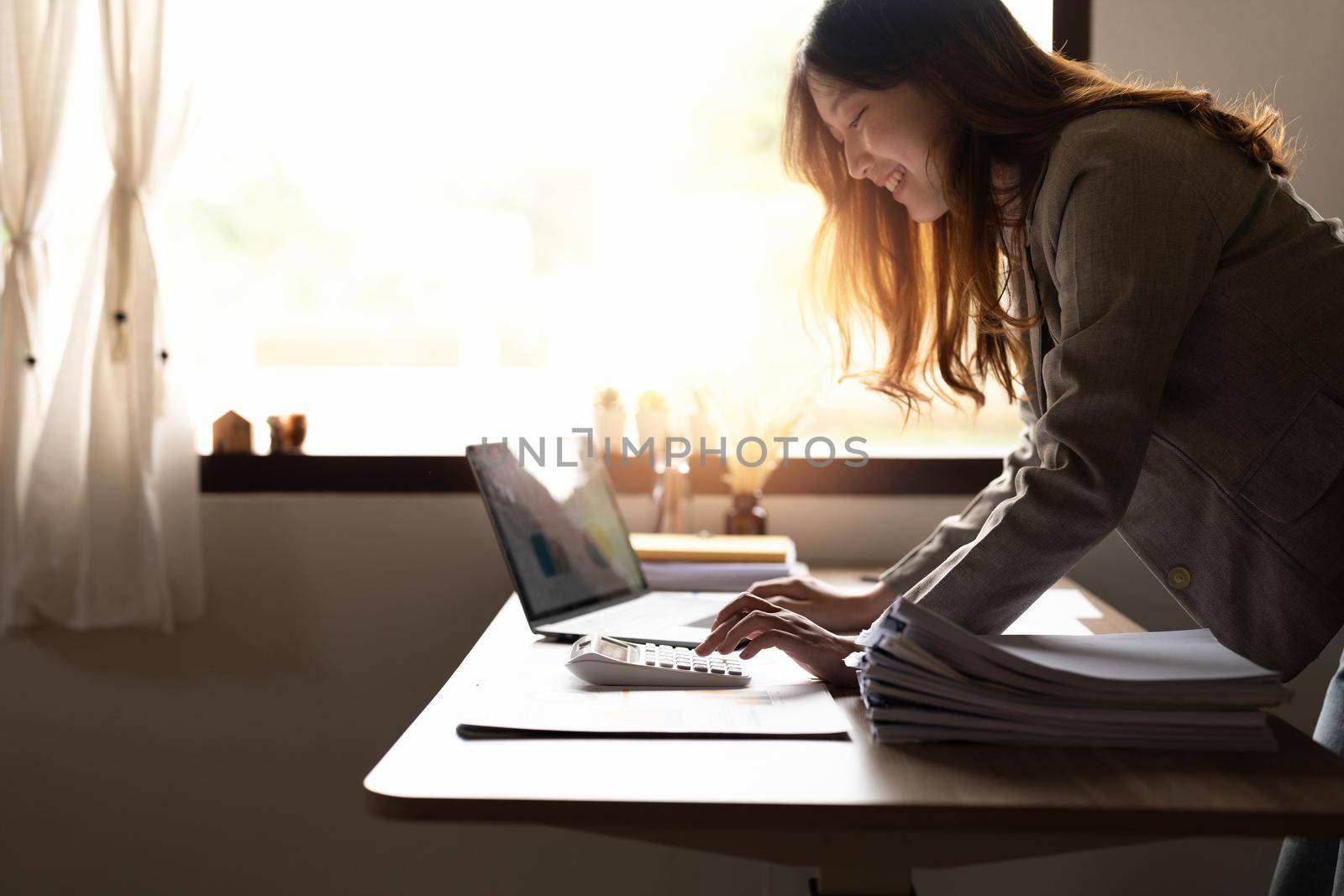 Business woman or accountant working on calculator to calculate business data, accountancy document and laptop computer at office, business concept.