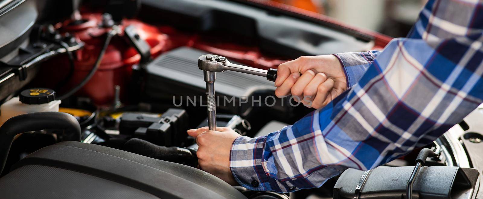 Female auto mechanic unscrewing a nut to replace a car spark plug
