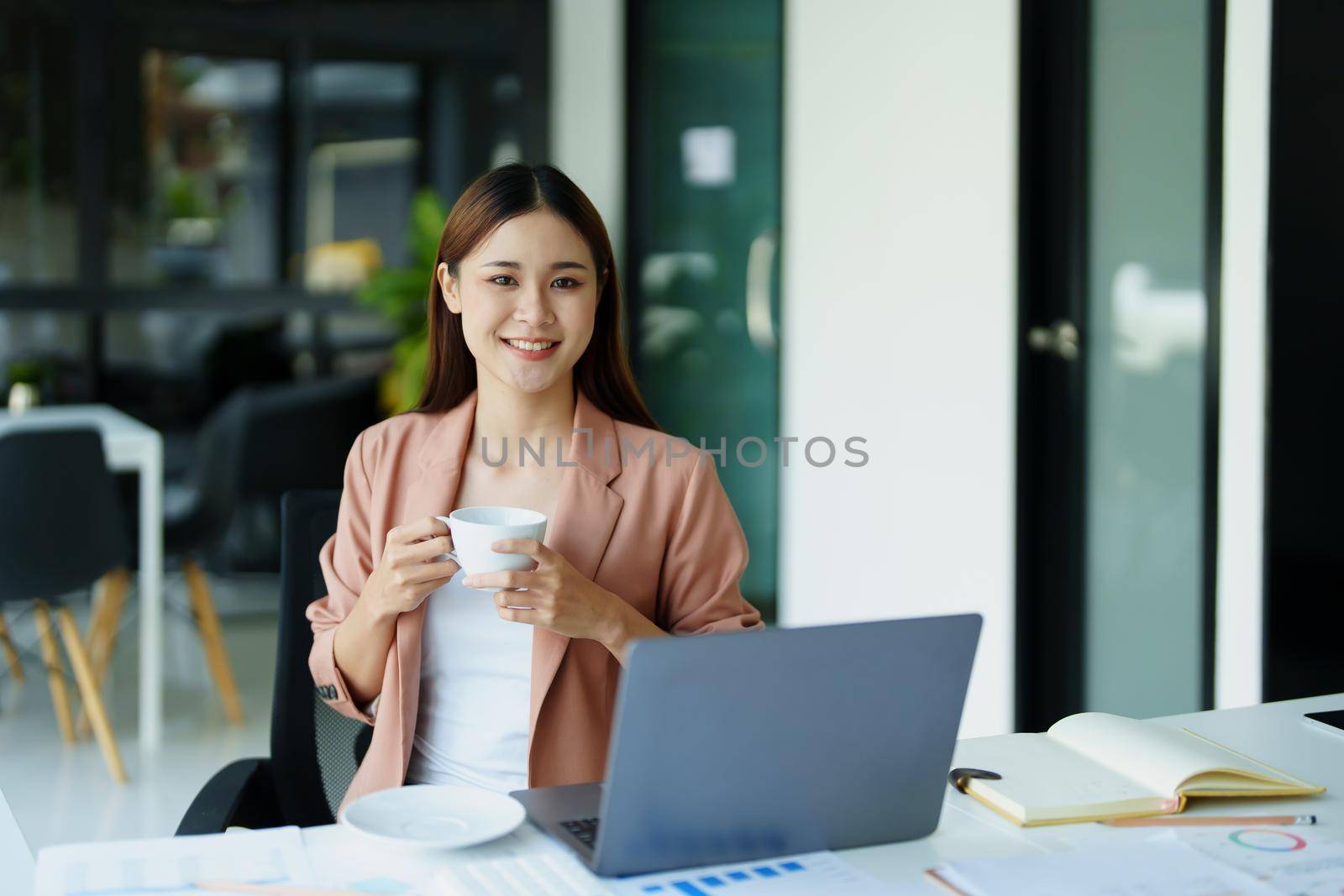 Portrait of a woman taking a coffee break while using a computer. by Manastrong