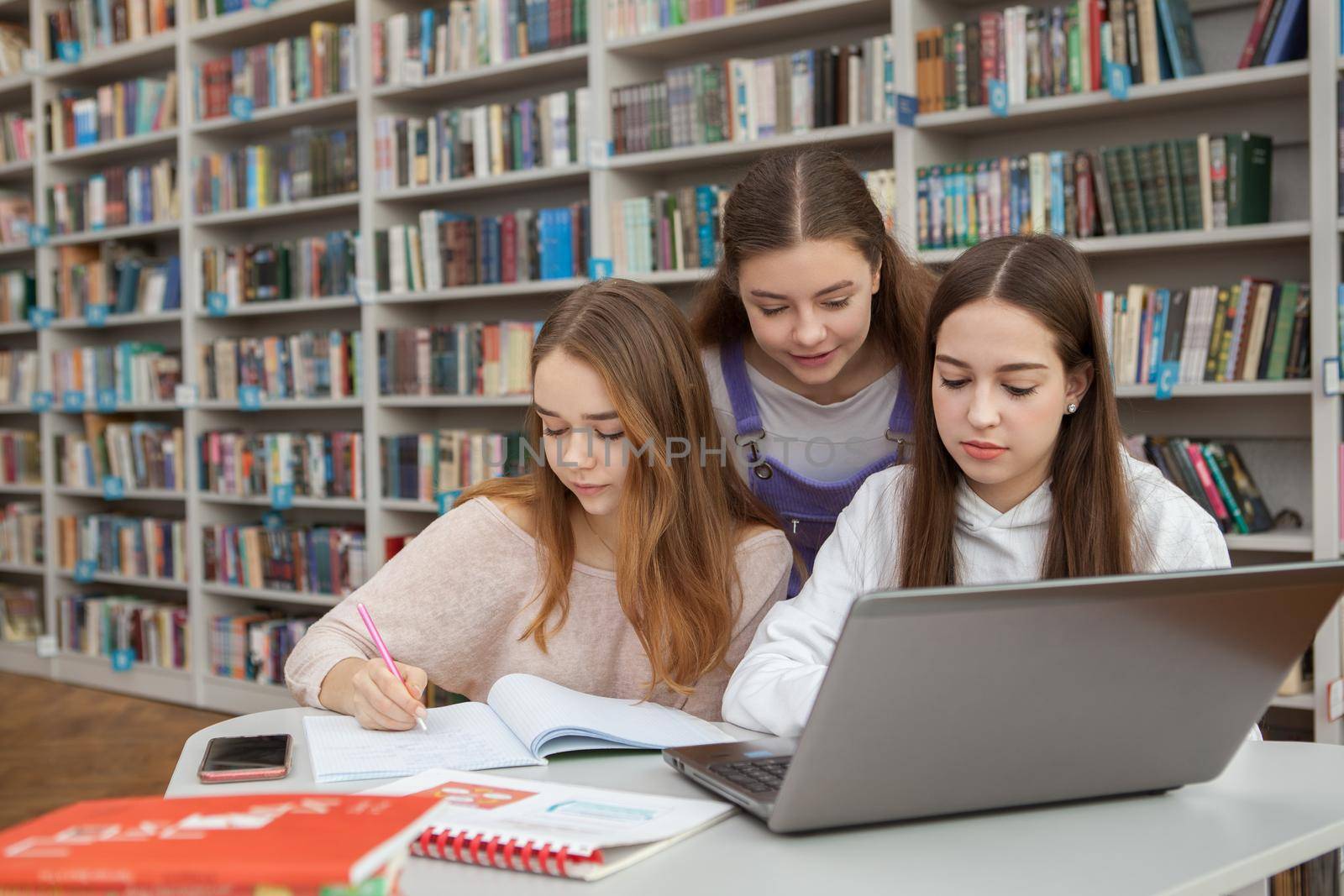 Three teenage girls studying together at school library, copy space