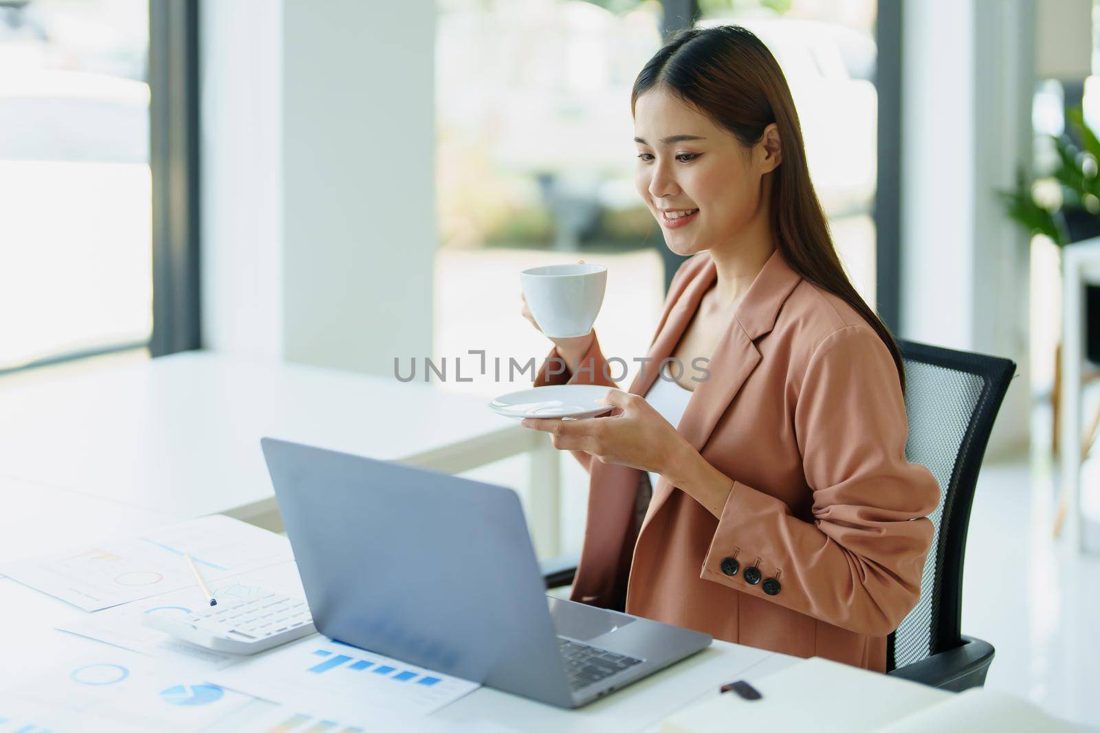 Portrait of a woman taking a coffee break while using a computer. by Manastrong