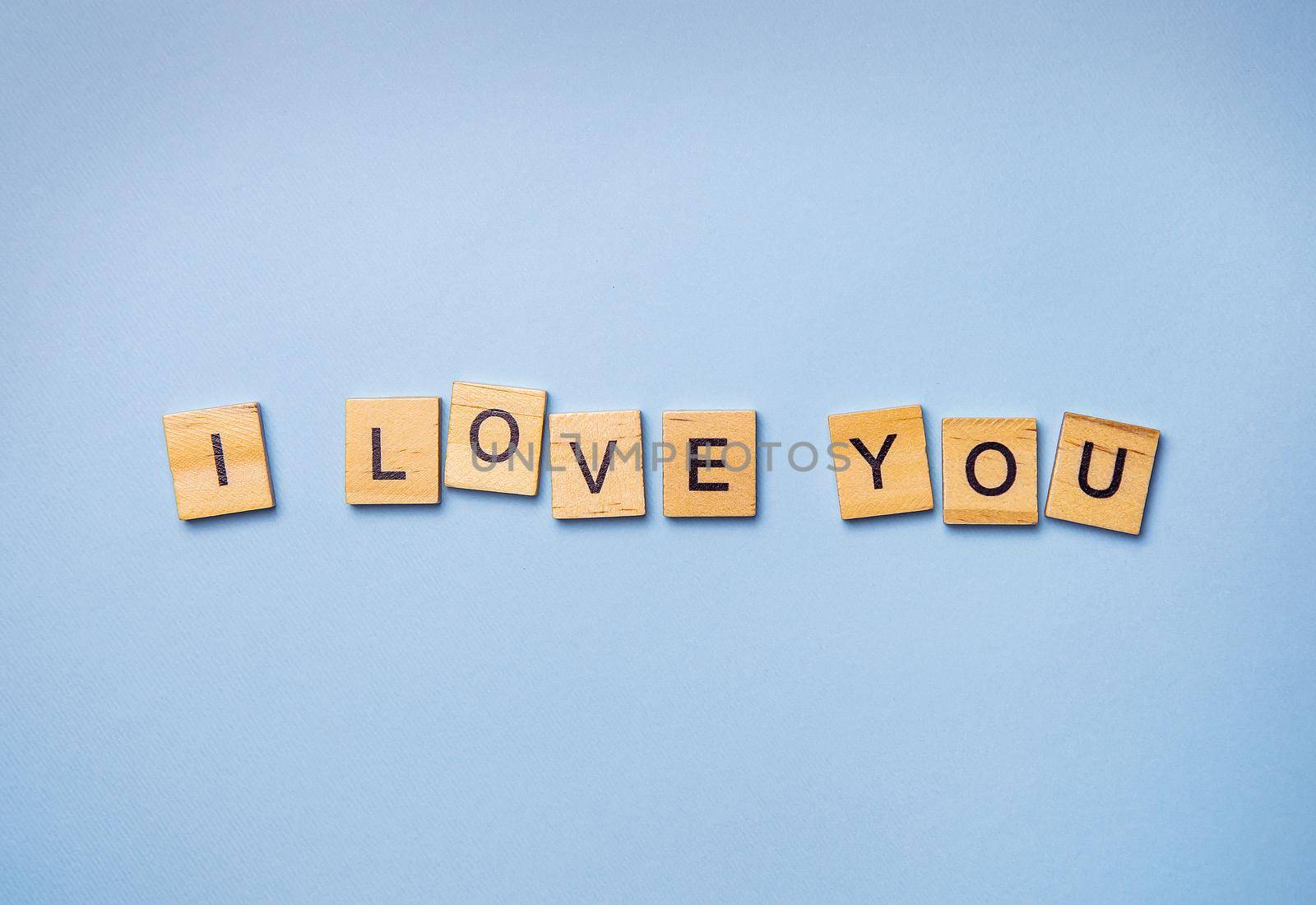 Inscription I love you in wooden square letters on a light blue background. Ready postcard, banner, place for an inscription. by sfinks