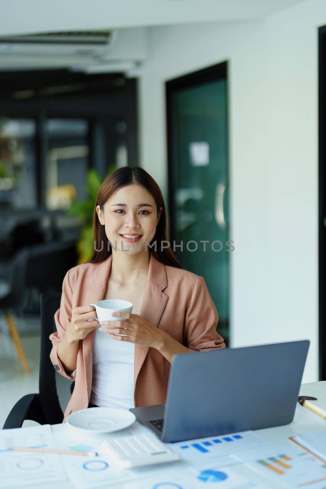 Portrait of a woman taking a coffee break while using a computer. by Manastrong