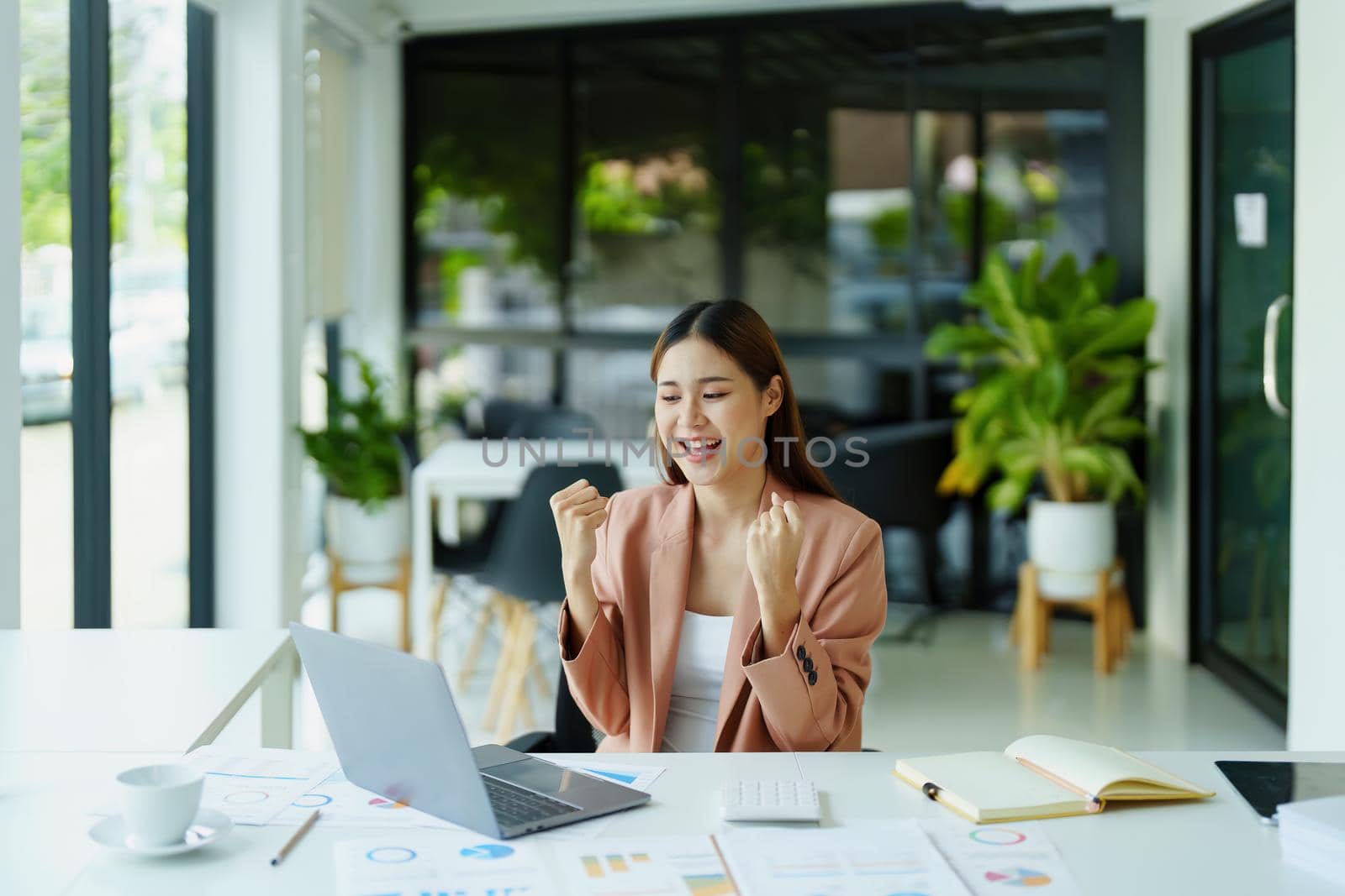 young Asian woman using a computer showing joy at the sales target.