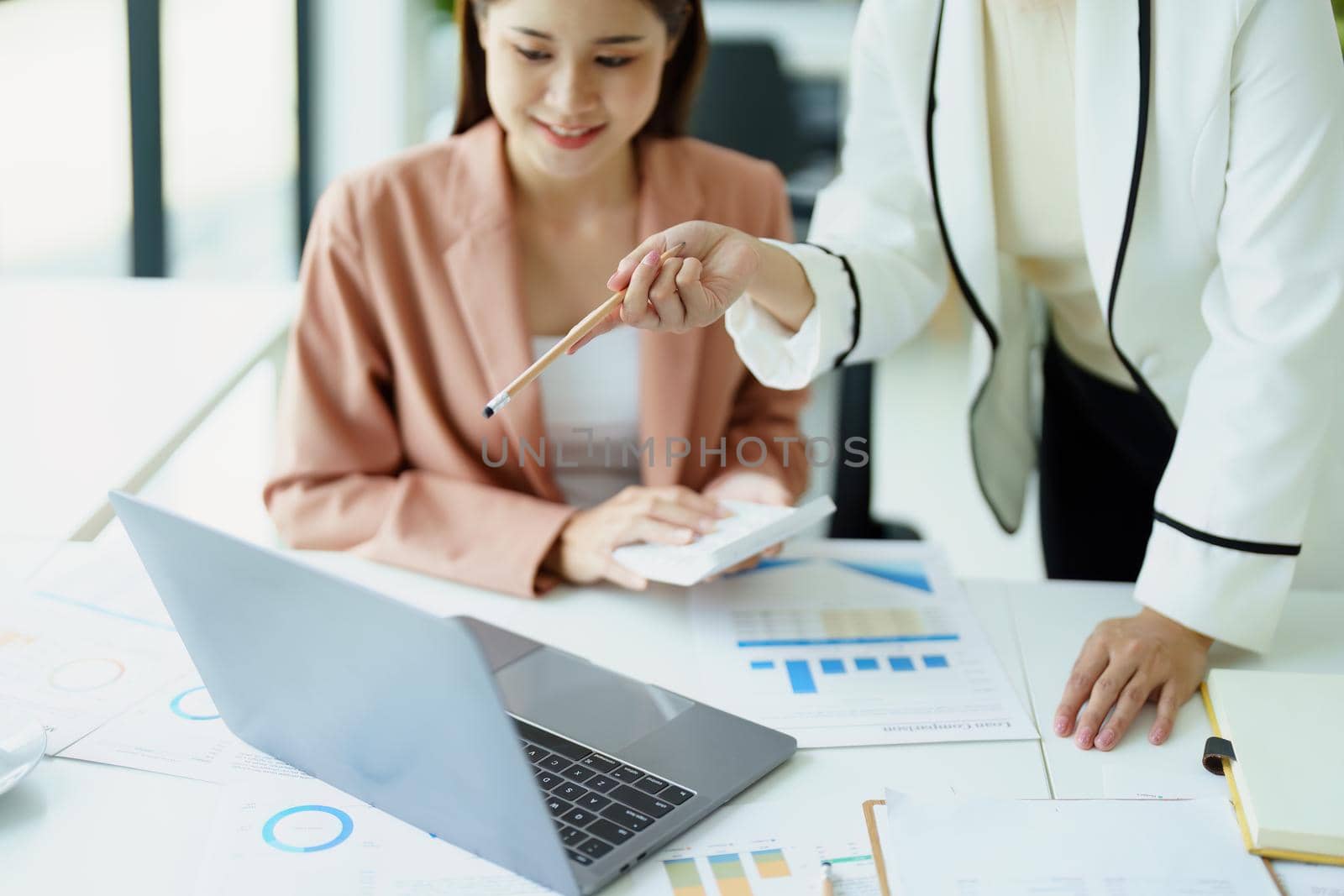 A portrait of two beautiful female employees discussing how they use computers to plan their marketing goals.