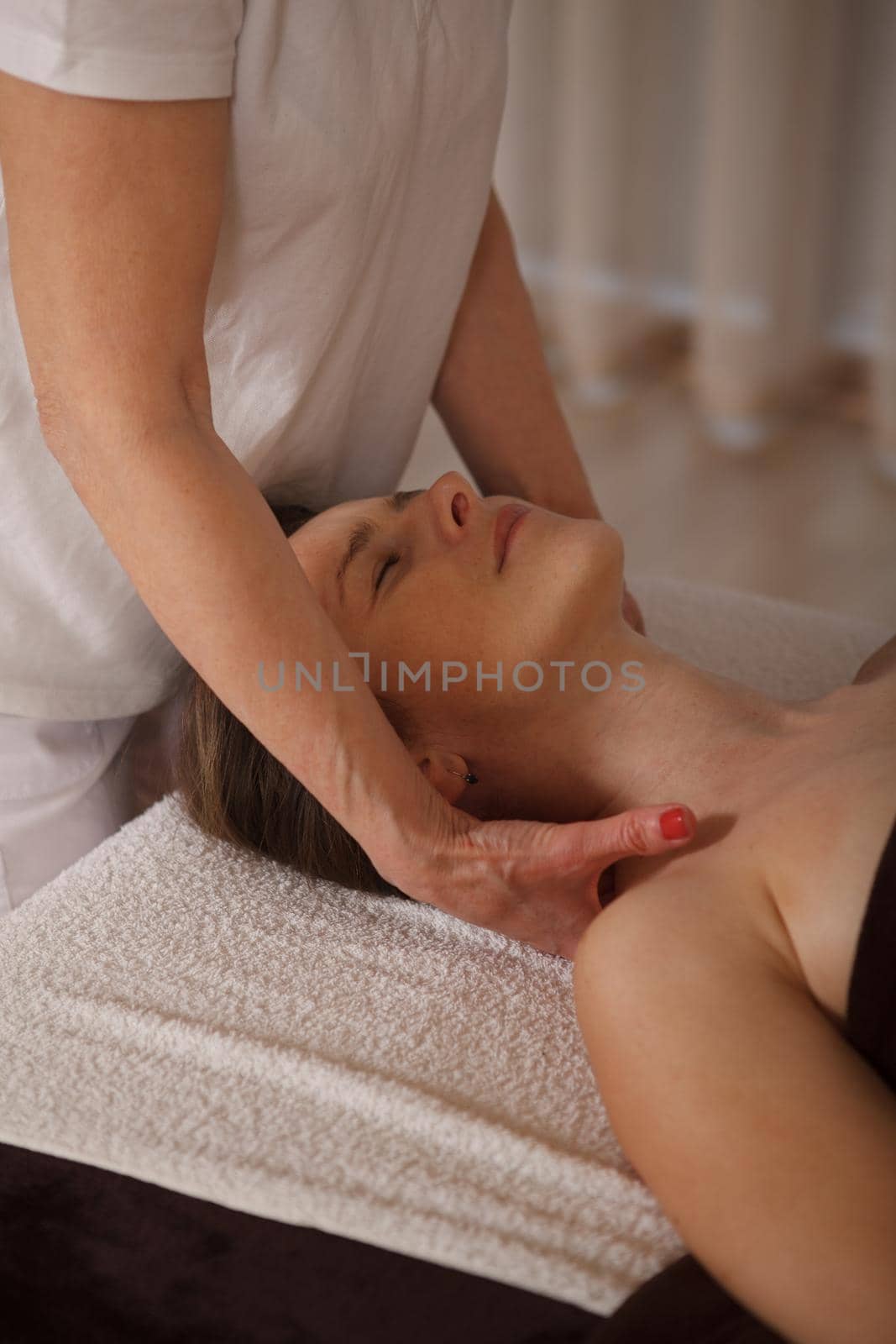Vertical shot of a relaxed mature woman enjoying professional shoulder massage