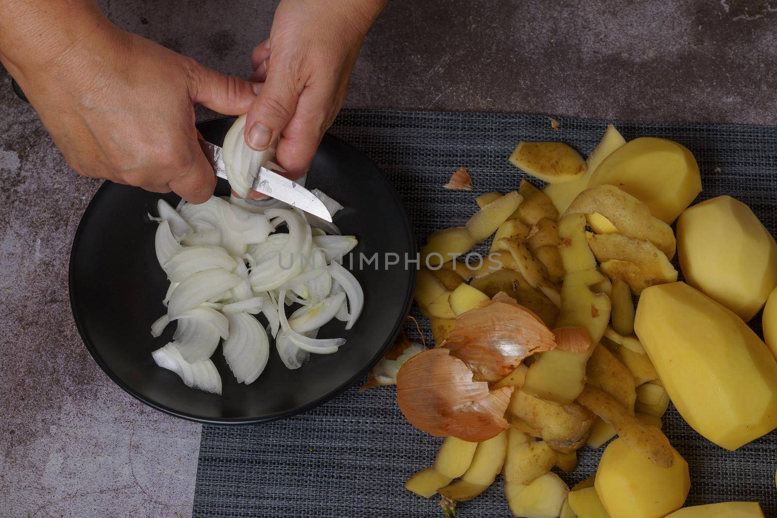woman cutting onion on a black plate by joseantona