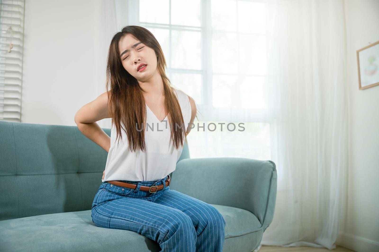Asian woman holding her lower back feeling painful waist hurt massage by Sorapop