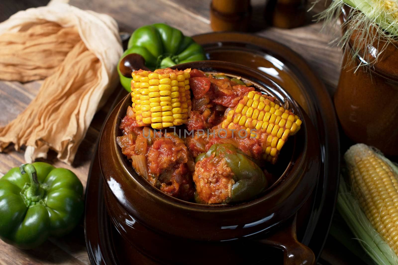 stuffed bell peppers with corn on the cob stewed in tomatoes, still life on wooden boards, traditional autumn dishes. High quality photo