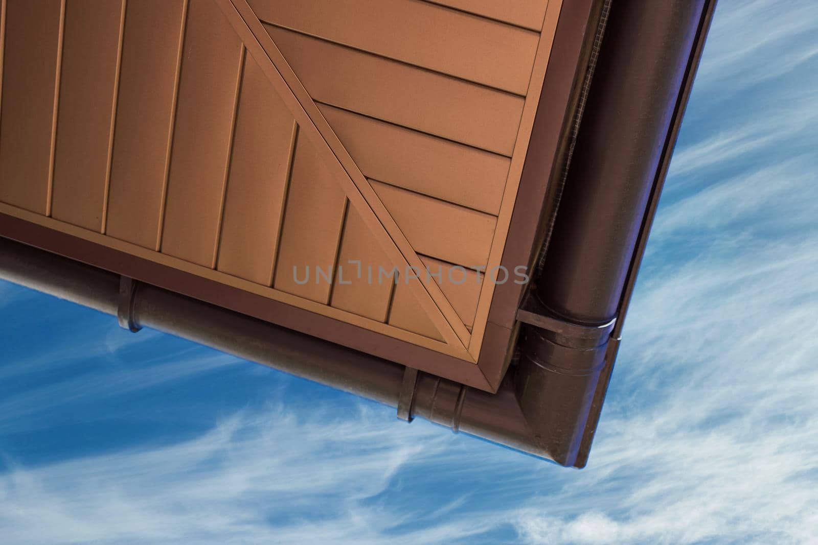 Roof cornice with gutter system against the blue sky.