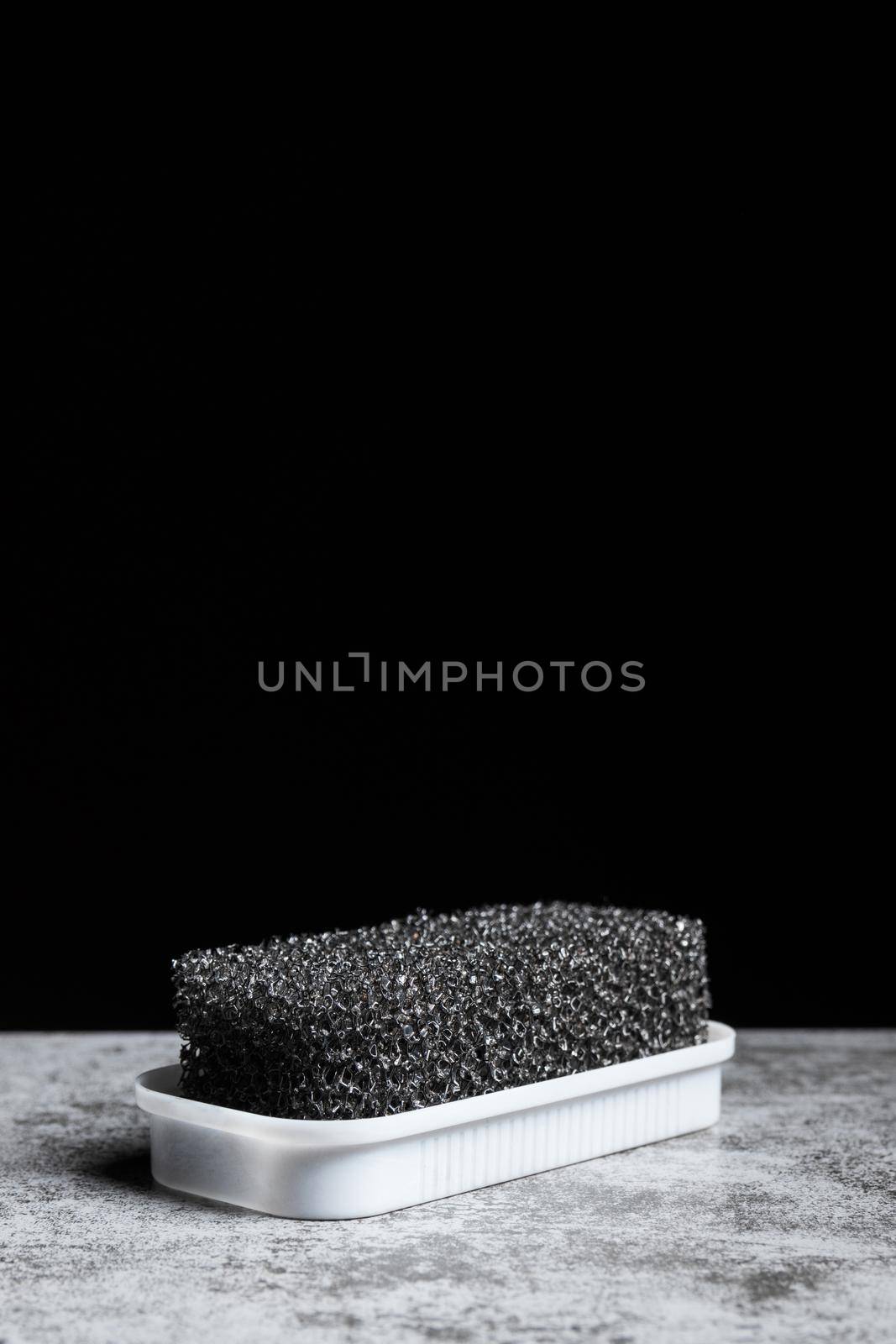 Foam sponge for suede shoes on a black background with copy space vertical.