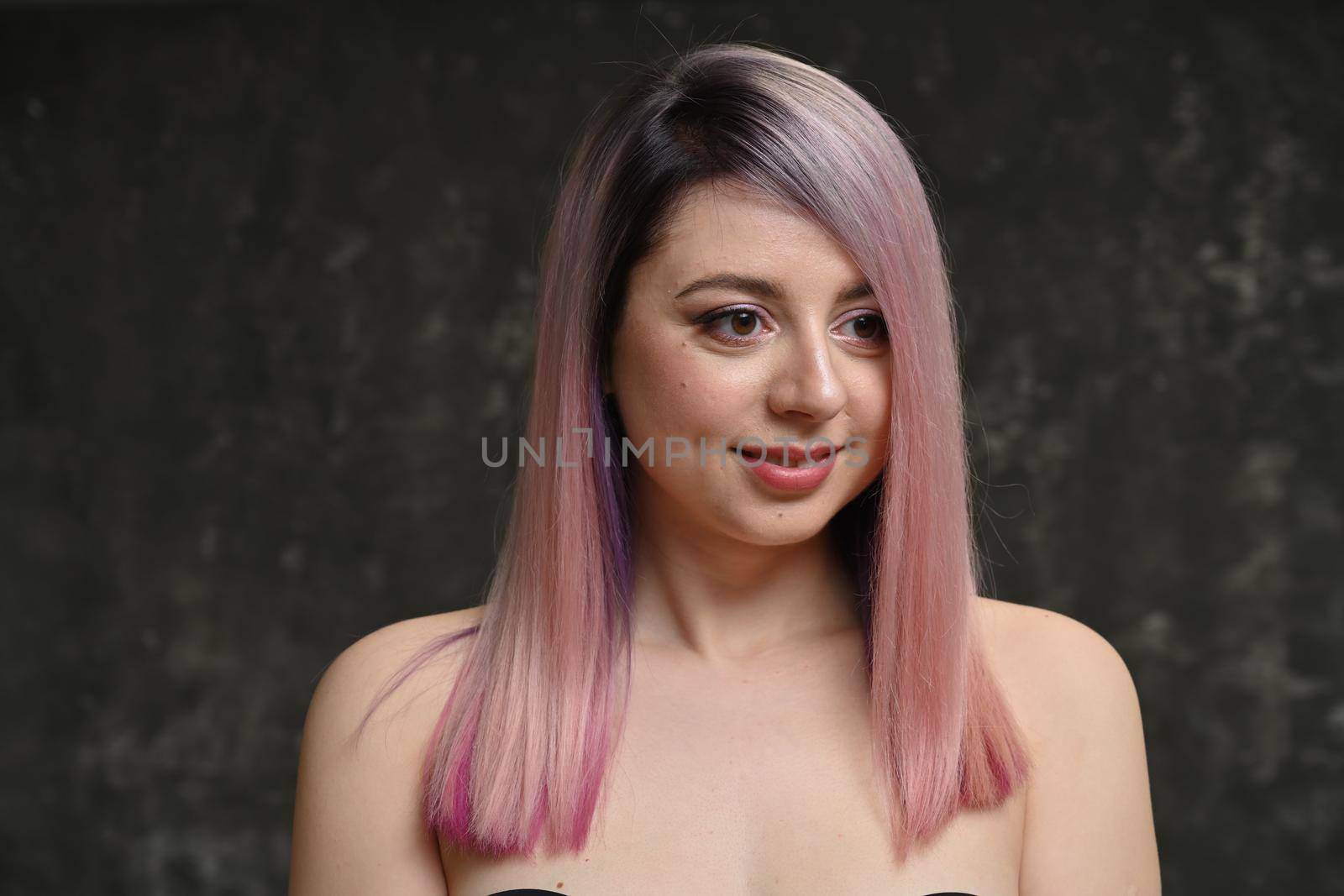 Portrait of young happy beautiful woman smiling and standing isolated on gray background. Young female girl with a perfect smile looking right.