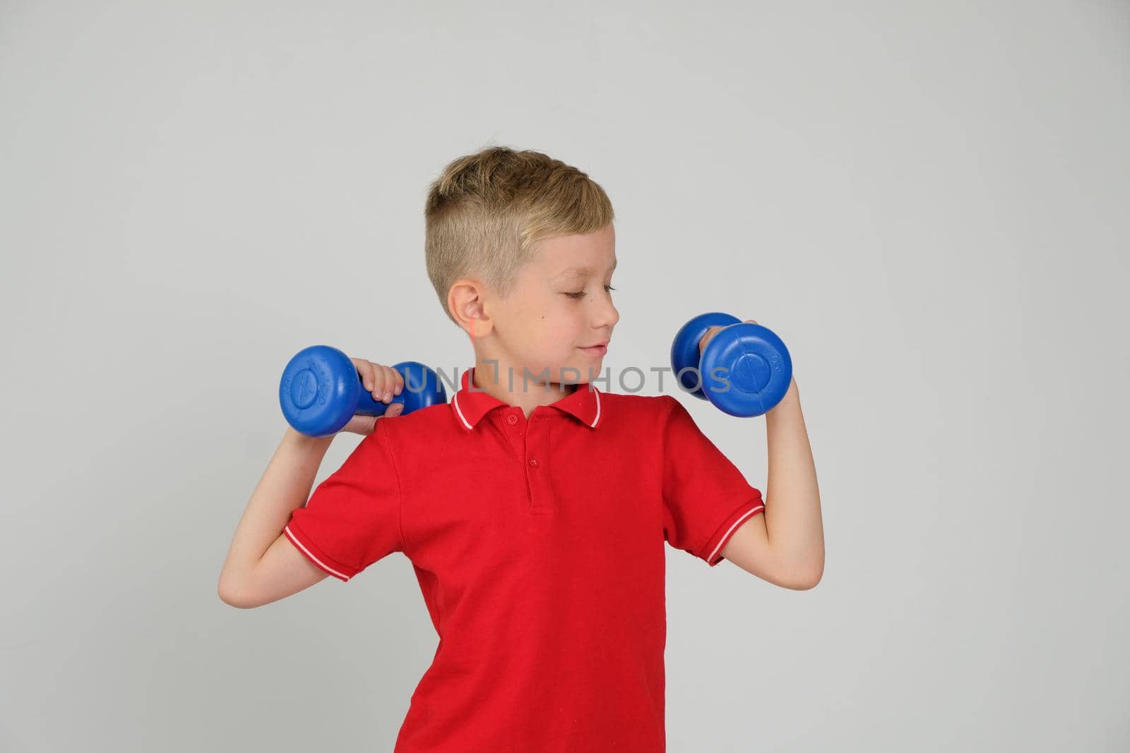 The little boy is engaged in fitness, he lifts dumbbells in the gym. Sport, health and physical Culture Concept by natus111