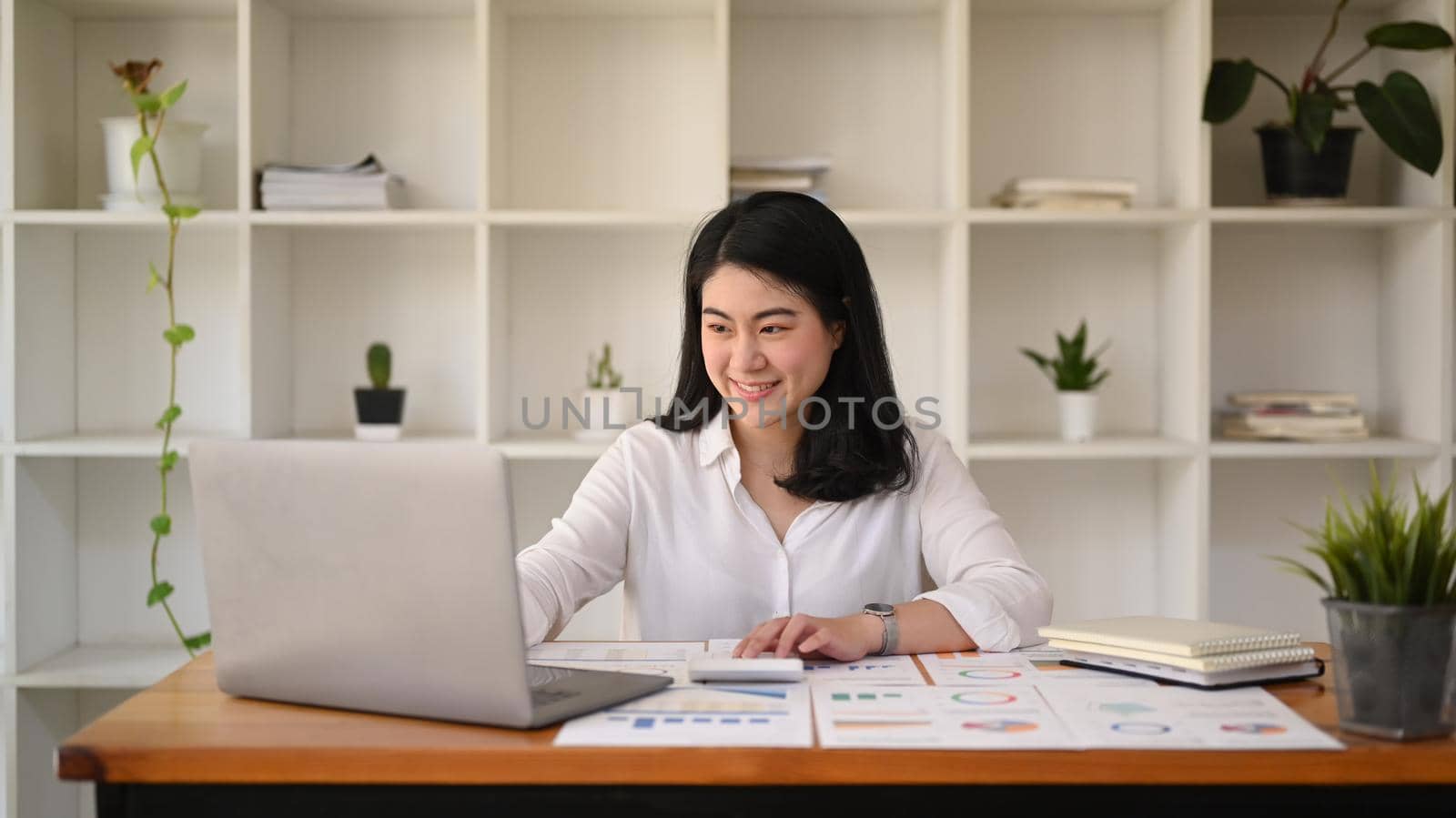 Beautiful asian woman working with laptop computer and preparing annual financial report at office desk.