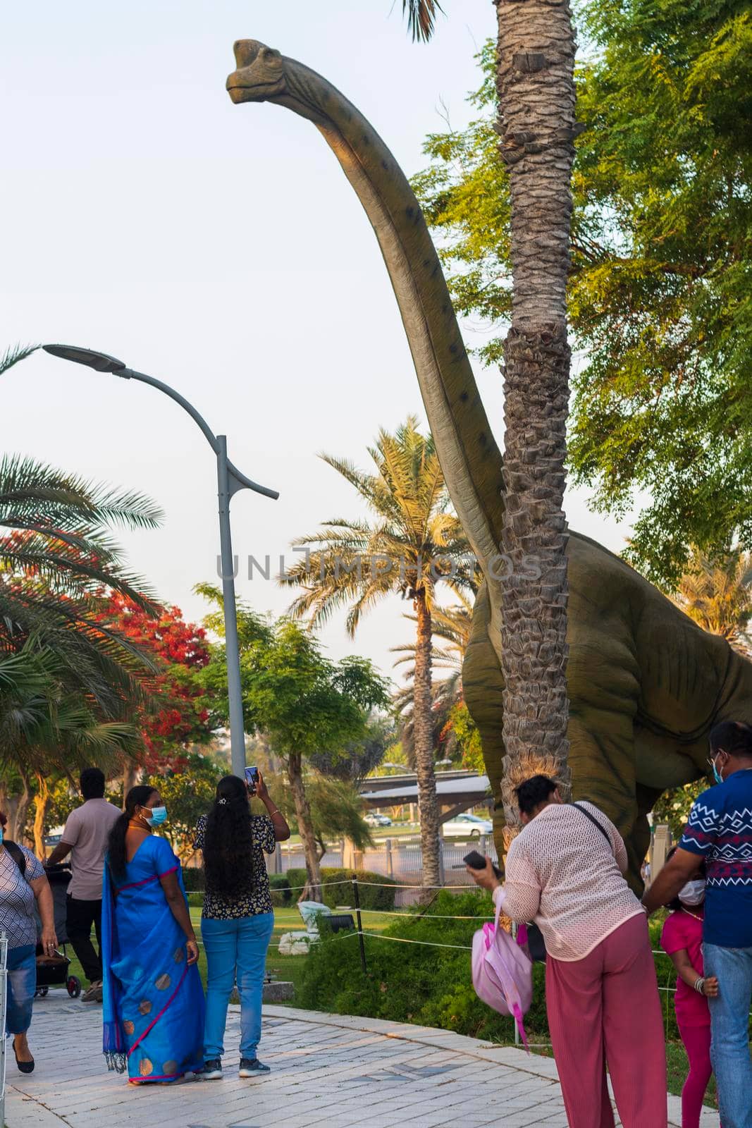 Dubai,UAE - 05.11.2021 -Visitors inspecting austrosaurus replica exhibit at dinosaur park.