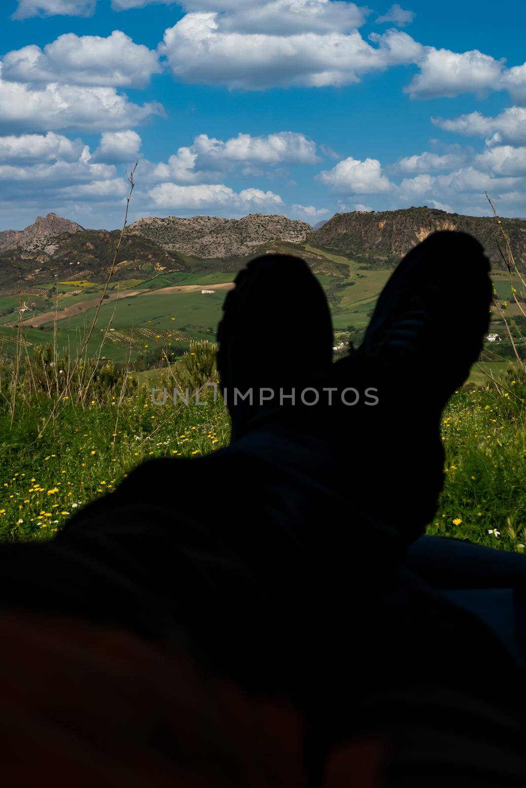 legs of man in shadow lying in his van with cloudy mountain scenery in background