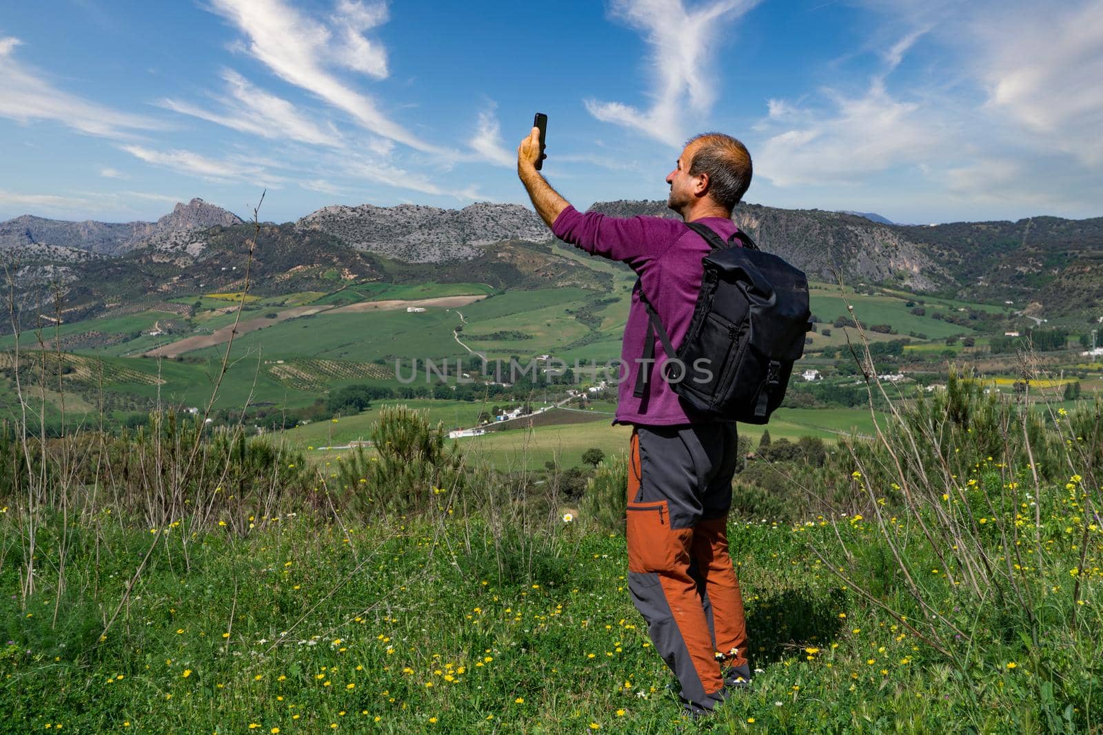lost man looking for coverage on his cell phone in the mountains to orient himself mountainous landscape in the background and cloudy sky