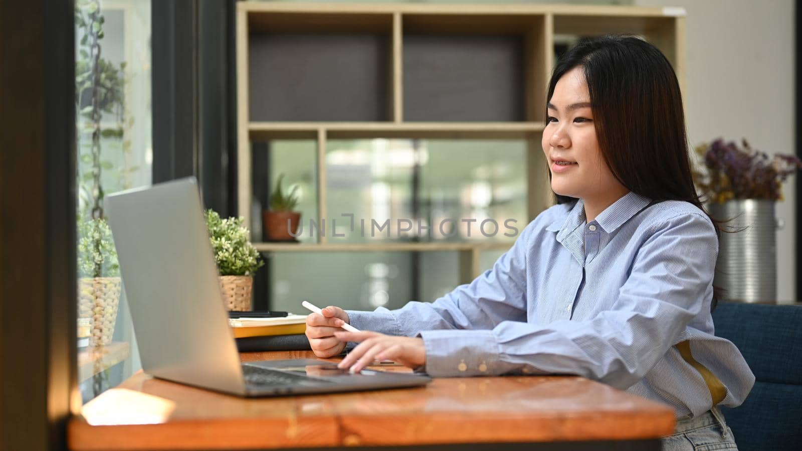 Asian woman office worker searching online information or typing business email on her laptop computer.